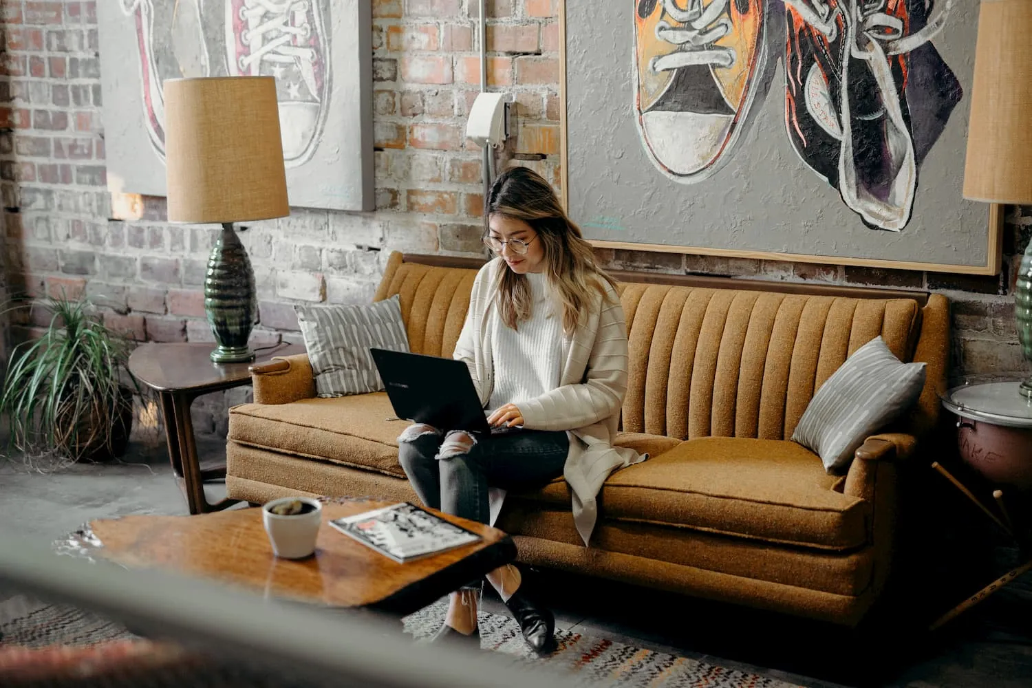 Frau mit Laptop auf dem Schoß sitzend auf einem Sofa